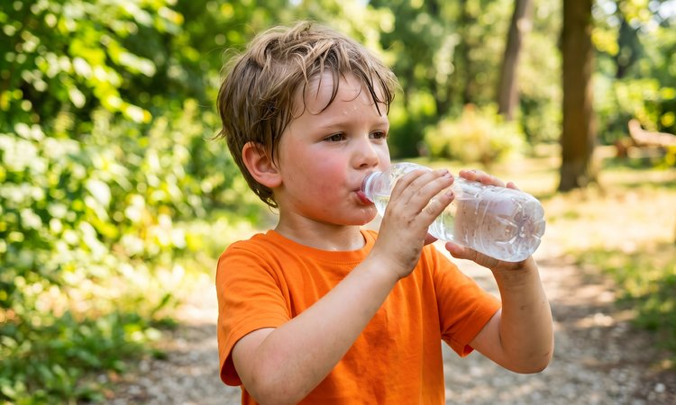 Ein schwitzender Junge trinkt aus einer Wasserflasche